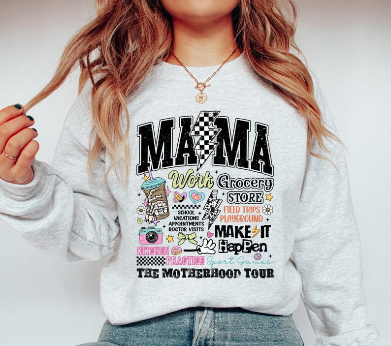 May include: Gray sweatshirt with a graphic print that says "Mama Work Grocery Store" and includes illustrations of a coffee cup, a camera, a heart, and a lightning bolt. The text "The Motherhood Tour" is printed below the graphic.