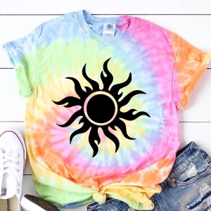 May include: A tie-dye t-shirt with a black sun graphic. The shirt is a blend of light blue, pink, yellow, and green.