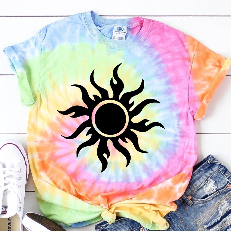 May include: A tie-dye t-shirt with a black sun graphic. The shirt is a blend of light blue, pink, yellow, and green.