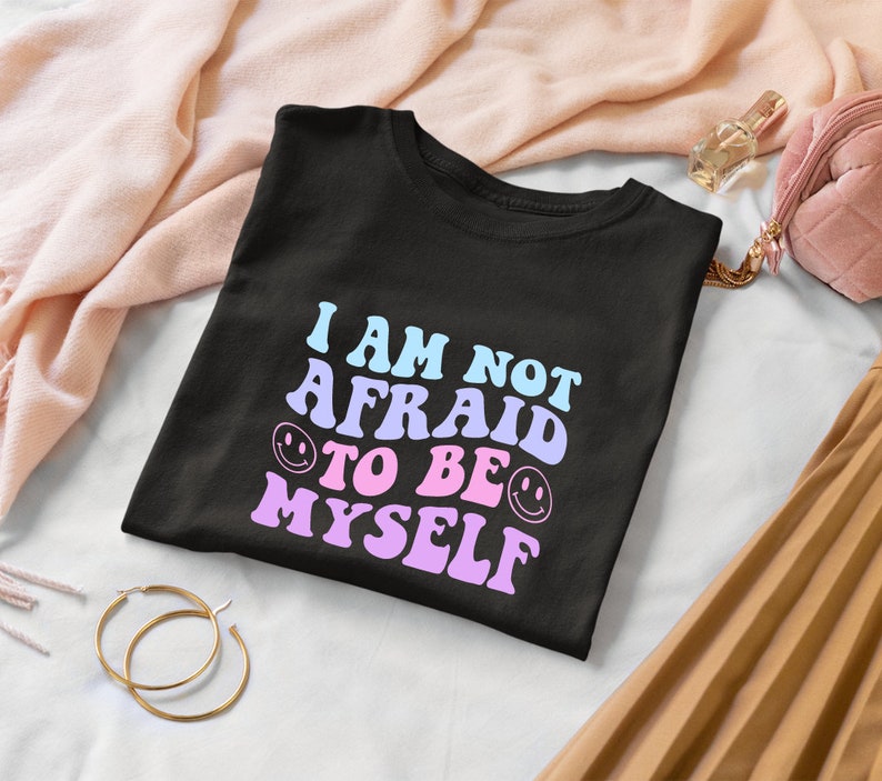 May include: Black t-shirt with the text "I am not afraid to be myself" in pink and blue with smiley faces.
