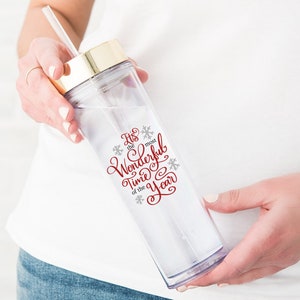 May include: A clear plastic tumbler with a gold lid and a red and grey design that says "It's the most Wonderful Time of the Year".