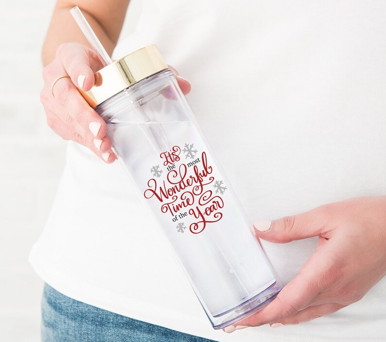 May include: A clear plastic tumbler with a gold lid and a red and grey design that says "It's the most Wonderful Time of the Year".