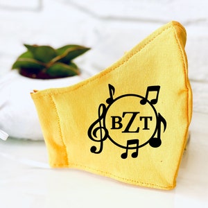 May include: Yellow fabric face mask with a black musical note design and the initials "BZT" in a circle.