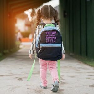 May include: A child wearing a pink shirt and blue and black backpack with the text "100 days of livin that kindergarten life" on the back.