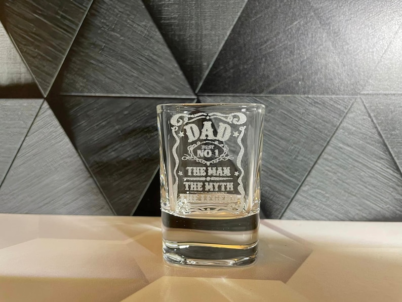 May include: A clear glass shot glass with an etched design that says "Dad Best No. 1 The Man The Myth".