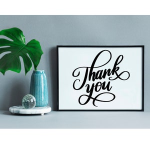 May include: A black framed print with white background featuring the text "Thank you" in a decorative script font.