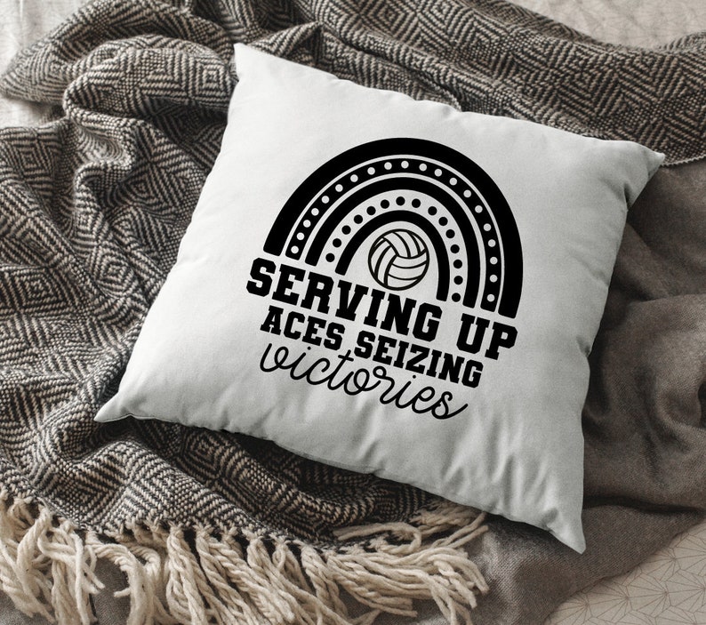K&ouml;nnte beinhalten: Ein wei&szlig;es Kissen mit schwarzem Text und einer schwarz-wei&szlig;en Volleyballgrafik. Der Text lautet "Serving Up Aces Seizing Victories".