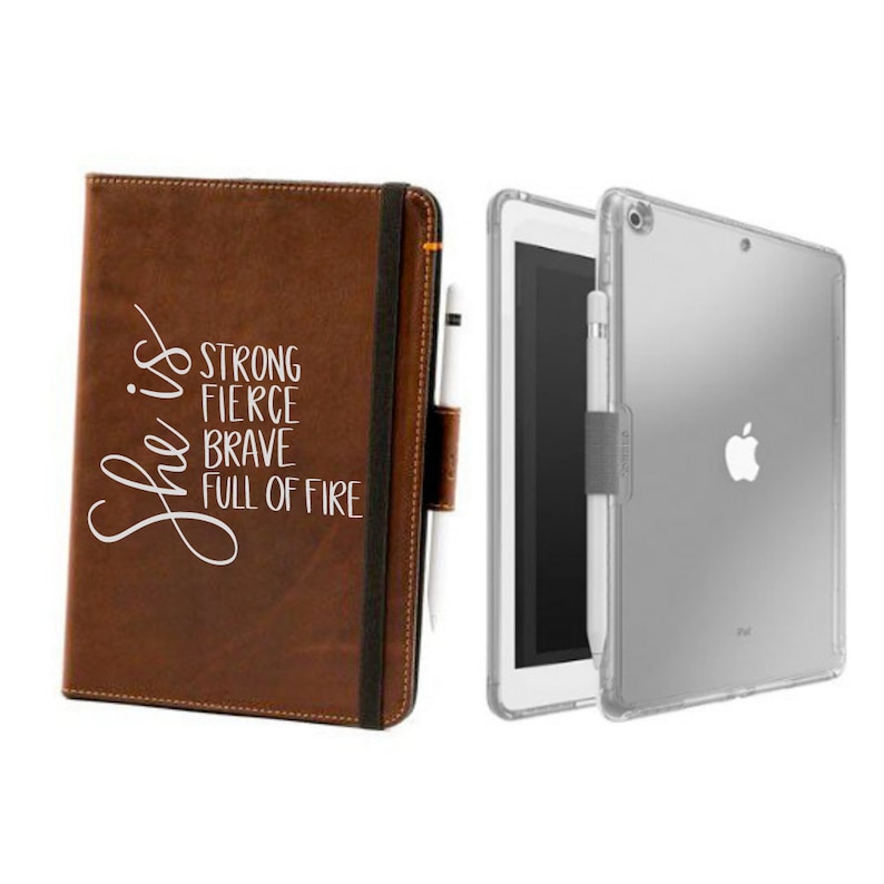 May include: A brown leather iPad case with a white inscription that reads "She is strong fierce brave full of fire". The case is closed and has a black elastic band to hold it closed. A clear plastic iPad case is also shown in the image.