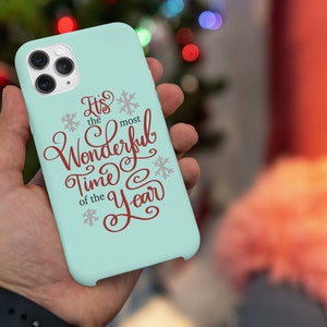 May include: A light blue phone case with a white snowflake design and the text "It's the most Wonderful Time of the Year" in red.