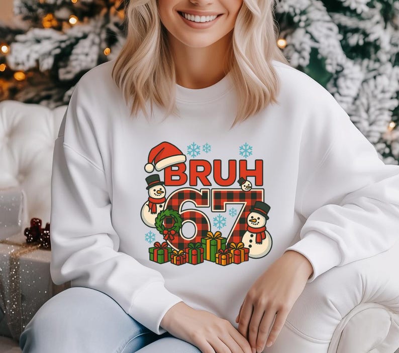 May include: White sweatshirt with a Christmas-themed graphic. The graphic includes the word "BRUH" in red letters with a Santa hat, the number "67" in a red and black plaid pattern, snowmen, snowflakes, and wrapped gifts.