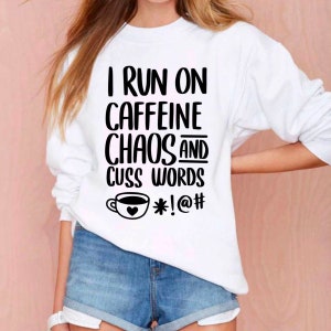 May include: White sweatshirt with black text that reads "I run on caffeine chaos and cuss words *!@#" with a coffee cup graphic.