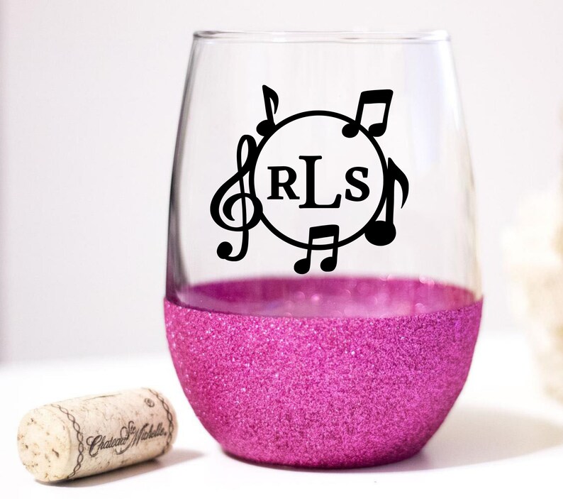 May include: A pink glitter stemless wine glass with a black vinyl decal of musical notes and the monogram "RLS".