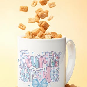 May include: White ceramic mug with the words "Fourth Grade" in a pastel, patchwork design. The mug is filled with cereal, with more cereal pieces falling into it. A blue bow and pencil graphic is on the mug.