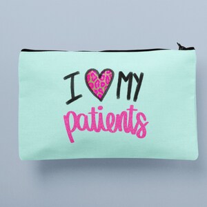 Puede incluir: Una bolsa de cremallera azul claro con el texto "I &hearts; MY patients" en letras negras y rosas. El coraz&oacute;n tiene un estampado de leopardo rosa.