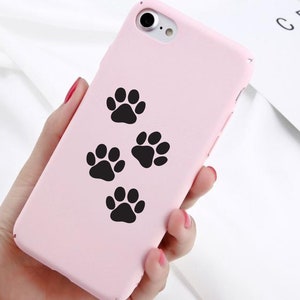 May include: A pink phone case with four black paw prints on it.