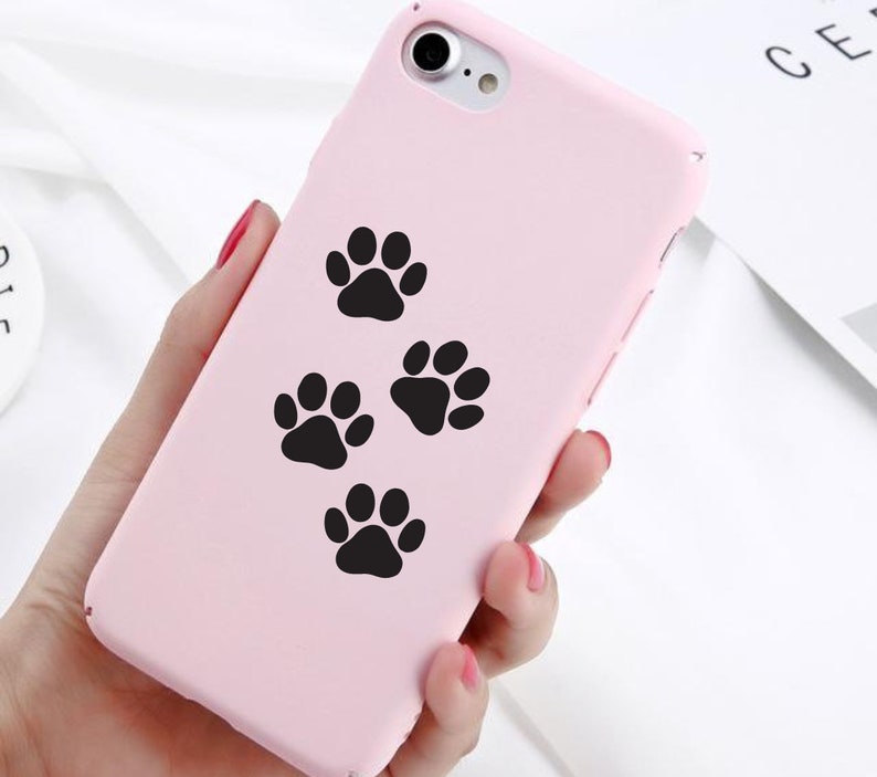 May include: A pink phone case with four black paw prints on it.