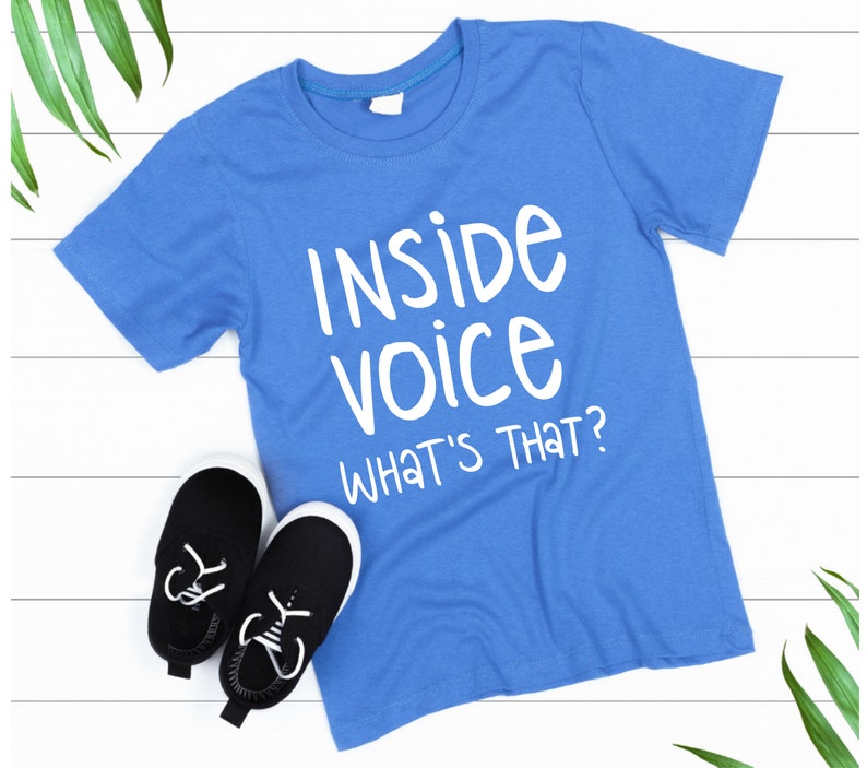 May include: A blue t-shirt with white text that reads "Inside voice What's that?"