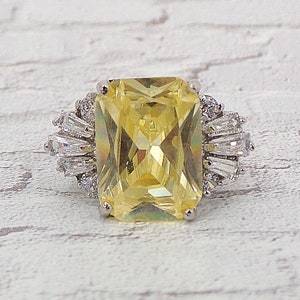Large light yellow cubic zirconia ring in a rectangle shape stone and made with baguette and round clear cz stones on each side Size 8