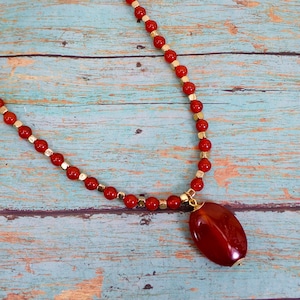 Red carnelian color glass bead necklace with carnelian oval stone pendant mixed with gold bead accents.