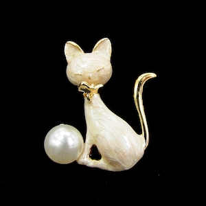 Precious cat pin brooch with white pearl designed in a beige enamel swirl color with gold plated tail and trim and a gold bow collar