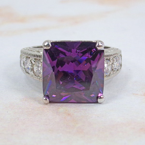 Purple fashion ring made with a square facet cut cubic zirconia stone, and with three round clear cz stones on each side. Size 7