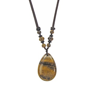 Large brown tiger eye teardrop shape stone pendant necklace suspended from smaller round stones and attached to brown fabric cord.