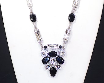 Spettacolare collana di cristalli neri e trasparenti progettata con un mix di cristalli rotondi, ovali e rettangolari incastonati in un pendente a forma di V.