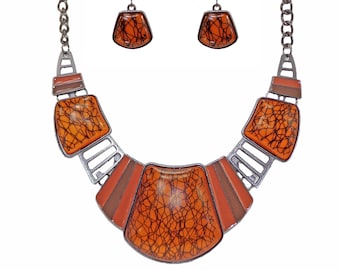 Magnifique ensemble collier et boucles d'oreilles orange conçu avec des perles cabochons en acrylique orange avec des motifs de volutes noires à l'intérieur.