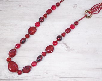 Long red beaded necklace designed with a mix of red acrylic bead shapes, red seed beads, and gold accent beads.
