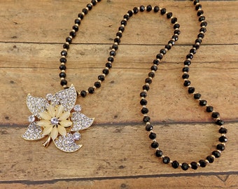 Large crystal flower pendant necklace with clear crystals and white cat eye stones.