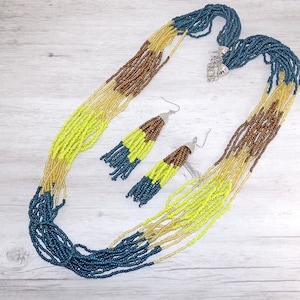 Long multi color seed beaded necklace and earrings.  It is created with 12 rows of seed beads in brown, beige, yellow, and blue.
