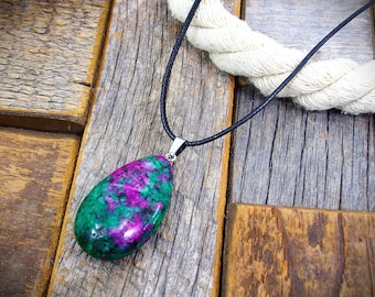 Natural ruby in zoisite stone pendant necklace in a teardrop shape and polished smooth and attached to a black cord necklace.