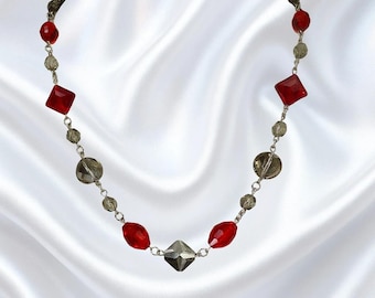 Collana scintillante di perline di vetro rosse e grigie, con perline di forma quadrata, rotonda e ovale unite tra loro: un accessorio di moda elegante e di tendenza.
