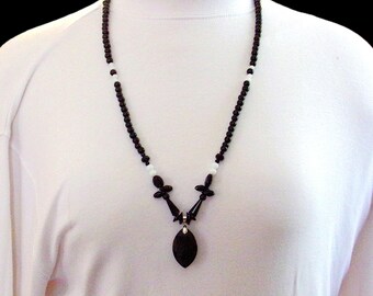 Black and white glass bead necklace with glass bead pendant made with round black beads around the neckline and a marquise shape pendant.