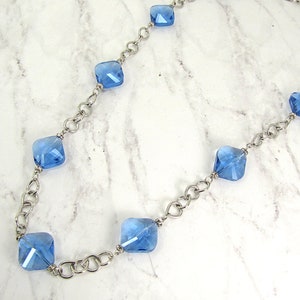 Long blue glass beaded necklace with silver plated tear drop shape links. Each glass bead is accented with small crystal spacer beads.