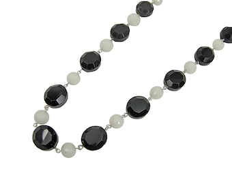 Collana di perline di vetro bianche e nere realizzata con grandi perle ovali nere in vetro sfaccettate collegate a perle rotonde in vetro bianco.