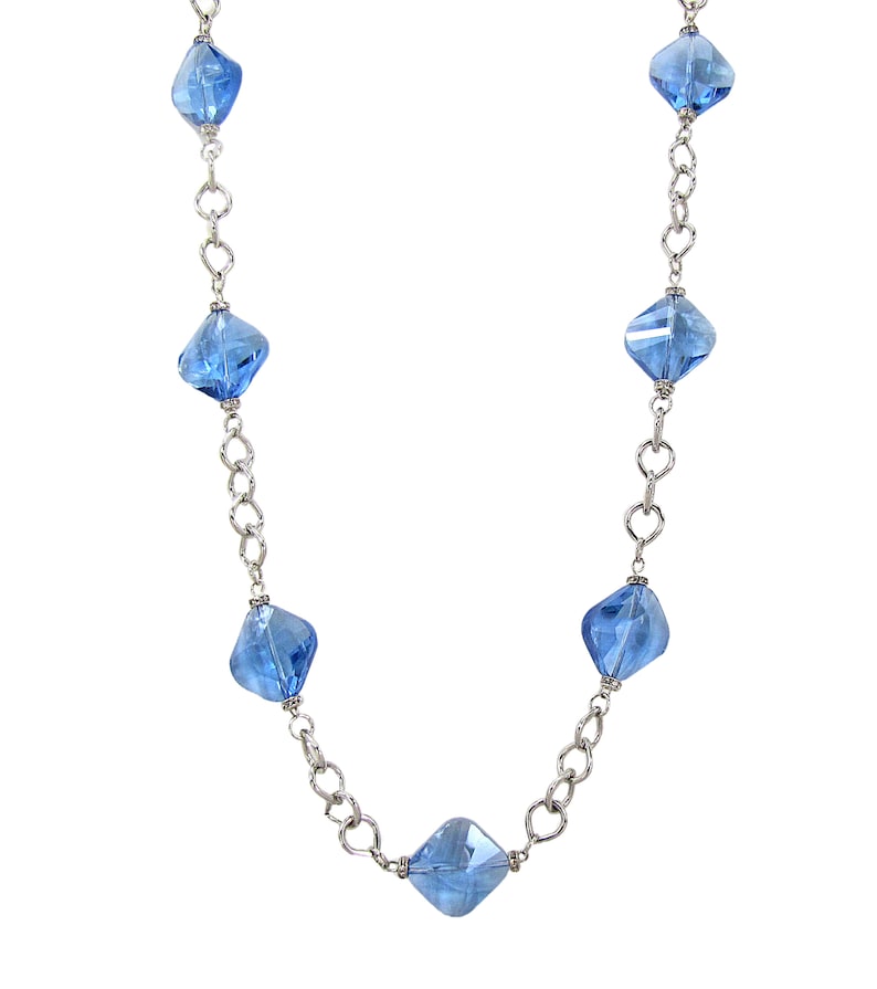 Each glass bead is accented with small crystal spacer beads. Long blue glass beaded necklace with silver plated tear drop shape links