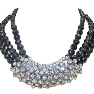 Large clear crystal statement necklace with three rows of black glass beads and a wide front cluster of round clear crystals..