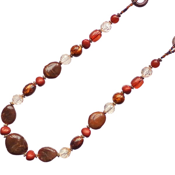 Long brown beaded necklace designed with a mix of brown acylic bead shapes, brown seed beads, and gold accent beads.