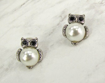 Cute owl earrings created with a white faux pearl and black crystal eyes in an antique silver plating finish.