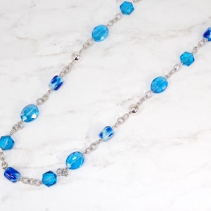 Long aqua blue color beaded necklace designed with a mix of glass and acrylic beads, and polished silver beads.