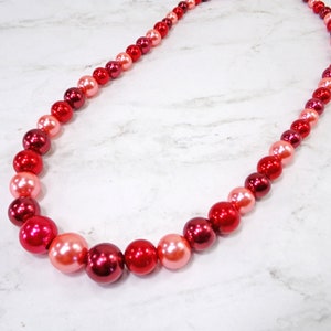 Red bead necklace designed with all round red beads in light and dark shades of red.