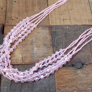 Pink multi strand glass beaded necklace created with five strands of beads in pink glass beads and pink seed beads.