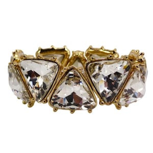 May include: A gold-toned bracelet featuring large, clear, triangular-cut crystals. The crystals are set in a gold metal frame, creating a sparkling and elegant accessory. The bracelet is designed with an elastic band for a comfortable fit.