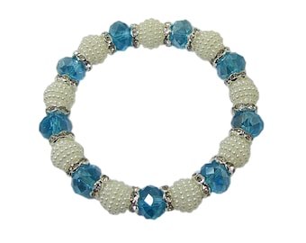 Bracciale elasticizzato con perline di vetro blu turchese con cristalli e perle bianche. È creato con perle di vetro sfaccettate e perle finte bianche.