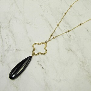 May include: A gold chain necklace with a black teardrop pendant and a gold four-leaf clover charm.