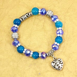 Heart charm stretch bracelet with blue glass beads and crystal beads.  Vintage looking haart charm with flower designs on it..