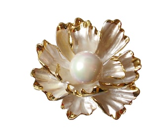 May include: A white flower brooch with gold accents and a pearl in the center.