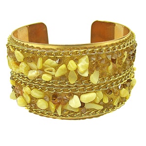 Brede manchetarmband met natuurlijke schelp en glaskralen in beige en goudkleuren met een touwketting eromheen.