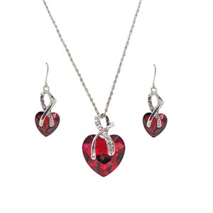 Conjunto de collar y aretes con colgante de corazón grande de cristal rojo con cristales transparentes en un engaste plateado. Conjunto de collar y aretes llamativos con forma de corazón.